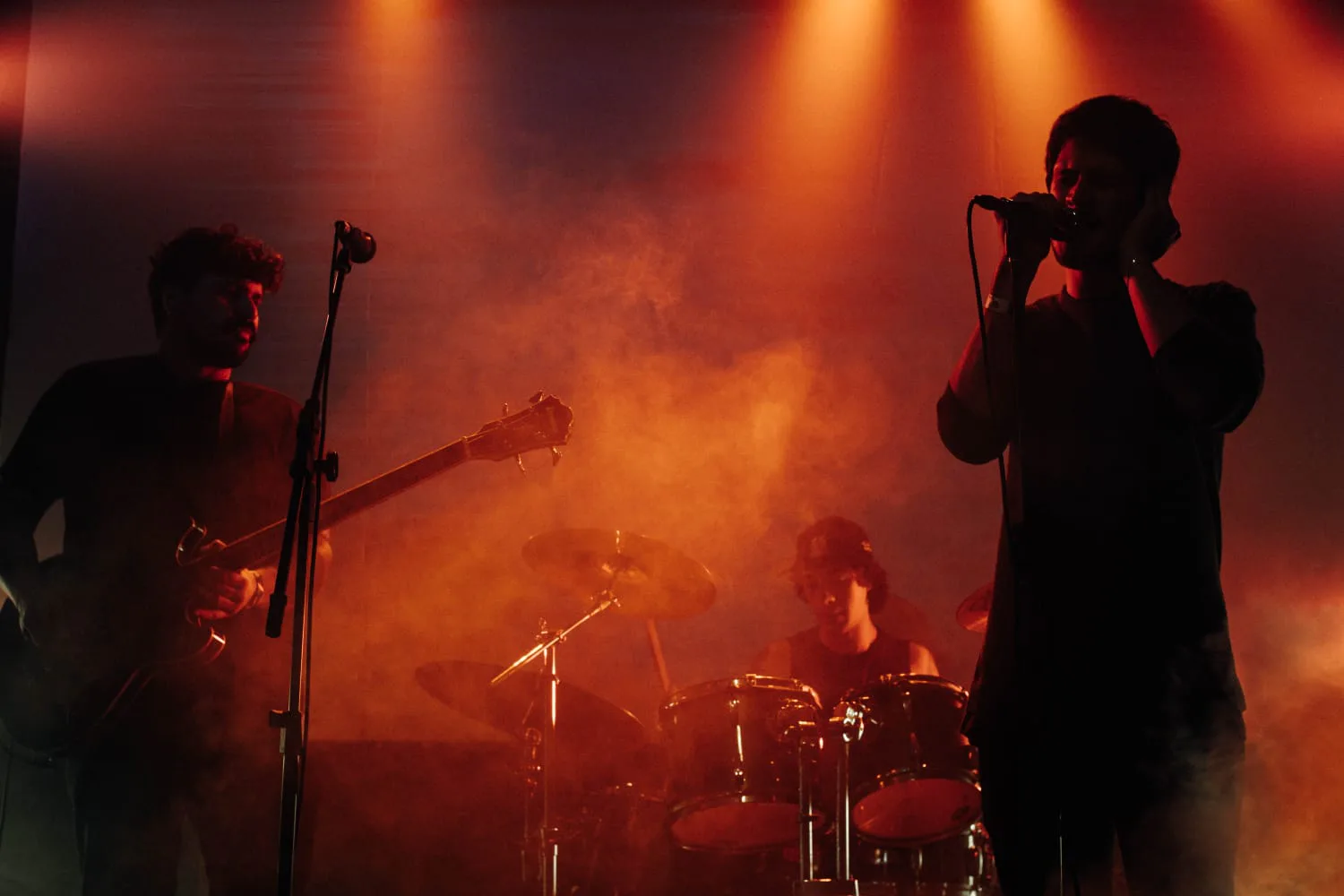 Os três integrantes da Curse Cult tocando ao vivo sob luz vermelha